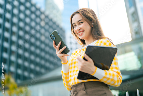 Fotografie cheerful woman in yellow checkered shirt holding smartphone and tablet, standing