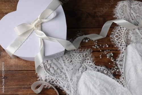 Gift box for wedding day and bridal dress on wooden background, flat lay