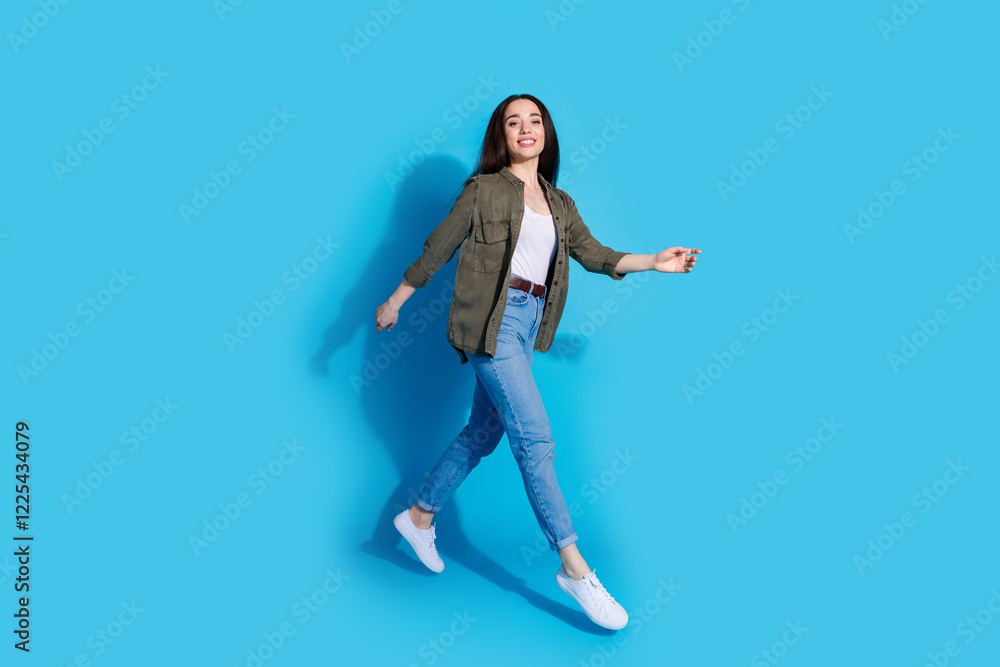 Confident young woman walking with a smile on a bright blue background Confident young woman walking with a smile on a bright blue background