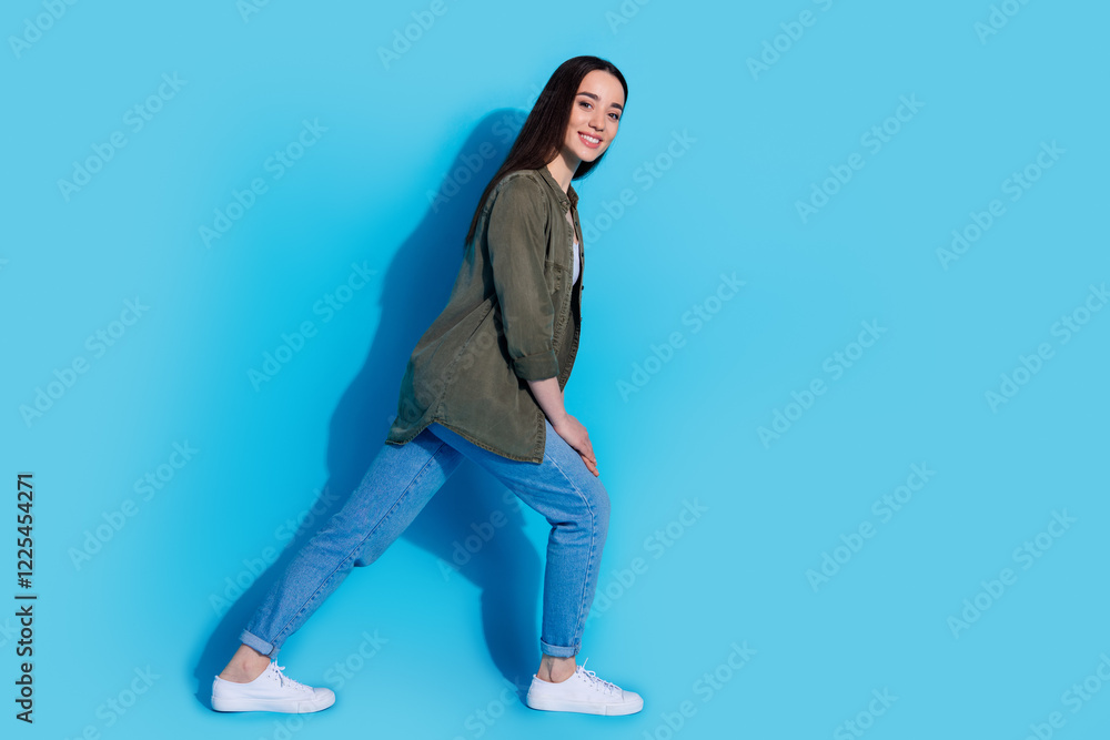 Fototapeta premium Portrait of a young woman casually dressed posing against a blue background with a smile
