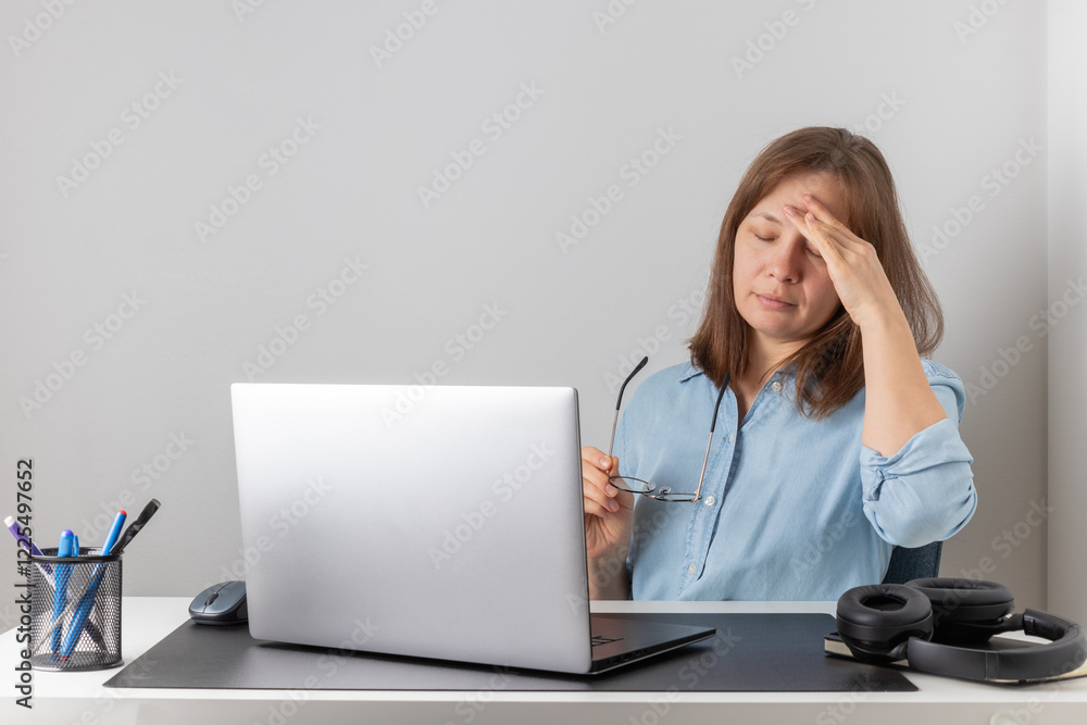 An overworked female freelancer is tired and stressed behind her laptop. Exhaustion and burnout problem of remote working. Woman struggles with fatigue and job-related stress An overworked female freelancer is tired and stressed behind her laptop. Exhaustion and burnout problem of remote working. Woman struggles with fatigue and job-related stress