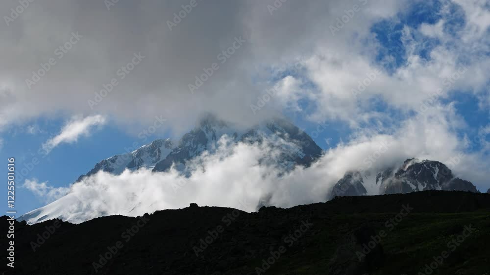 Timelapse of Kazbegi mountain in Caucasus mountain ridge. Snow-capped peaks with clouds moving around, time passing fast. Stunning nature scenery suitable for travel, adventure, nature lovers. Timelapse of Kazbegi mountain in Caucasus mountain ridge. Snow-capped peaks with clouds moving around, time passing fast. Stunning nature scenery suitable for travel, adventure, nature lovers.