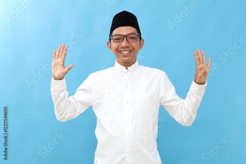 Asian muslim man raising nine fingers, isolated on a blue background. photo