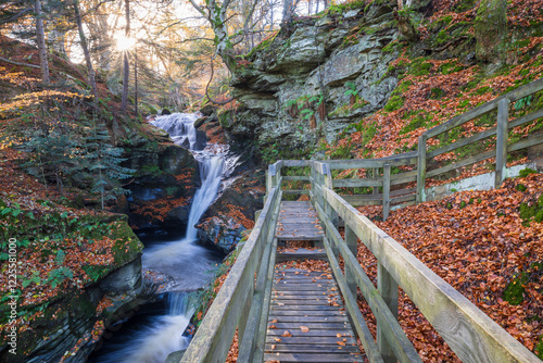 Wooden Boardwalk Leading to the Picturesque Falls of Acharn, Featuring a Flowing Waterfall and Mossy Rocks in the Scottish Highlands During Autumn photo