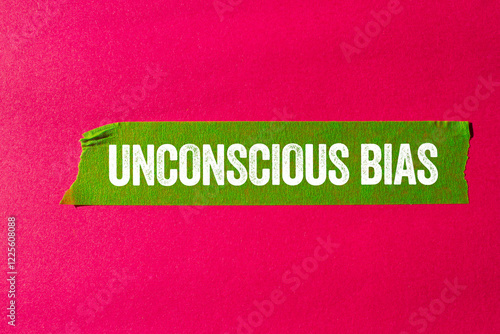 Unconscious bias message written on ripped torn green paper tape on pink background. Conceptual unconscious bias symbol. Copy space.