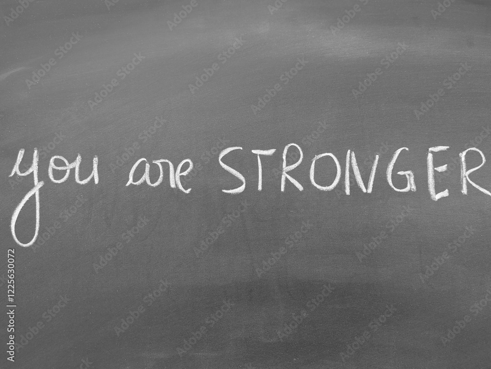 Fototapeta premium Motivational handwritten phrase 'You are stronger' on a blackboard background