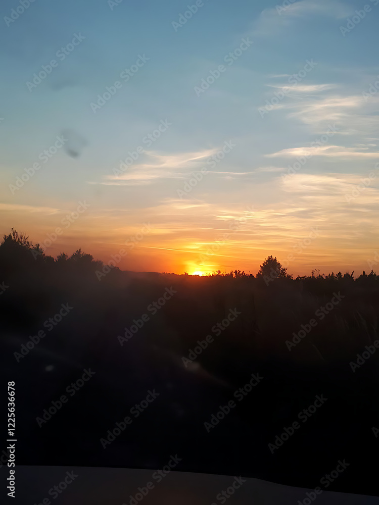 Obraz premium Stunning sunset view over a forest landscape with colorful sky and distant horizon