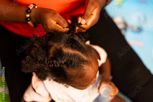 African mother plaiting her daughter's hair. African hairstyle, time for affection and bonding. photo