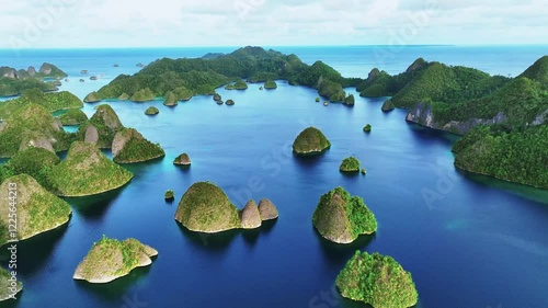 Aerial view of beautiful tropical islands and serene lagoon with scattered sandy shores and blue ocean, Raja Ampat Regency, Indonesia.
