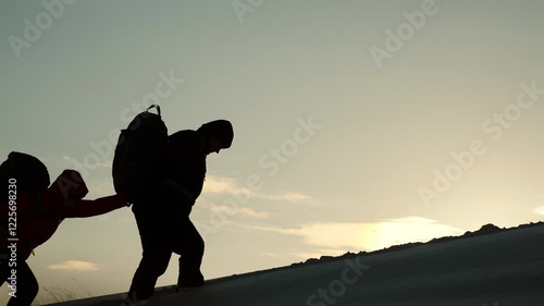 silhouette people climbers going forward mountain sunset. concept climbers with backpacks. teamwork. family trip mountains with backpacks winter sunset. campaign young successful winners. help hand
