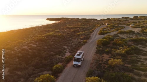 Aerial view of serene mangrove bay with a winding road and a campervan at sunset, Western Australia, Australia.