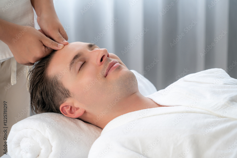 Caucasian man enjoying relaxing anti-stress head massage and pampering facial beauty skin recreation leisure in dayspa modern light ambient at luxury resort or hotel spa salon. Quiescent Caucasian man enjoying relaxing anti-stress head massage and pampering facial beauty skin recreation leisure in dayspa modern light ambient at luxury resort or hotel spa salon. Quiescent