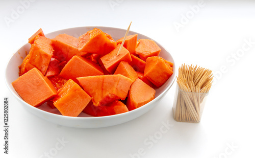 Sweet soft cut pieces of ripe papaya served on a plate with wooden picks isolated on white. photo