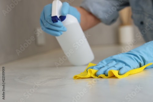 Fotografia Woman using cleaning product while wiping countertop with rag indoors, closeup
