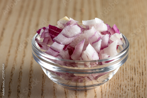 Close up of finely chopped red onion in a glass bowl.