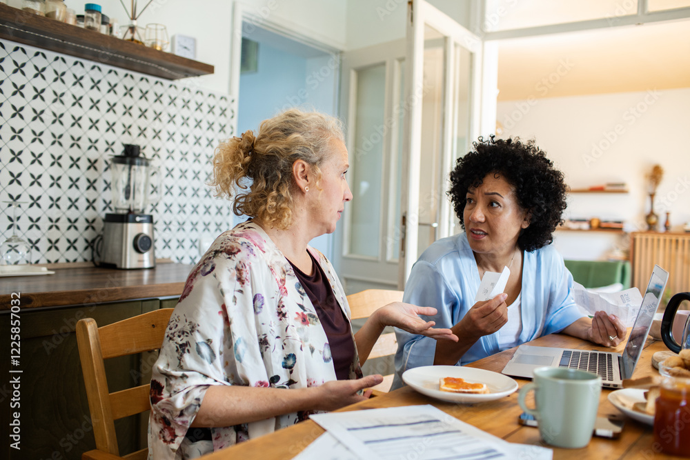 Lesbian couple eating breakfast together at kitchen desk Lesbian couple eating breakfast together at kitchen desk