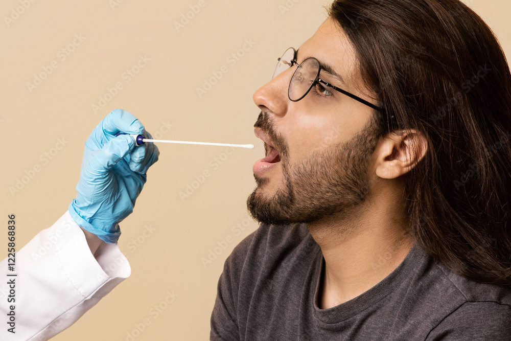 Female doctor in protective face mask making PCR-test for arab guy at clinic, nurse taking oral swab for coronavirus sample, beige studio background. COVID-19 diagnostic, treatment, prevention concept Female doctor in protective face mask making PCR-test for arab guy at clinic, nurse taking oral swab for coronavirus sample, beige studio background. COVID-19 diagnostic, treatment, prevention concept