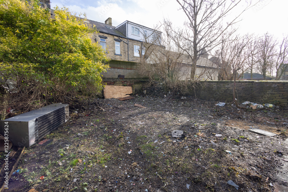 Photo of an extremely run down property garden showing rubbish in the unkept garden of a family home in the winter time