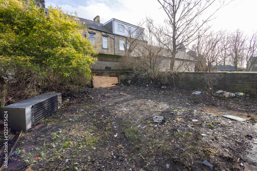 Photo of an extremely run down property garden showing rubbish in the unkept garden of a family home in the winter time photo