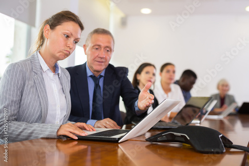Mature businessman prompts and helps businesswoman during a business meeting