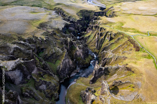 Breathtaking aerial drone view of a serene river winding through a majestic Fjadrargljufur Canyon in Iceland
