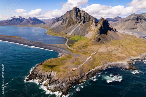 Scenic aerial drone view of Hvalnes Nature Reserve Beach, Hringvegur road, Hvalnes Lighthouse and amazing mountains in background by the Atlantic Ocean in Iceland photo