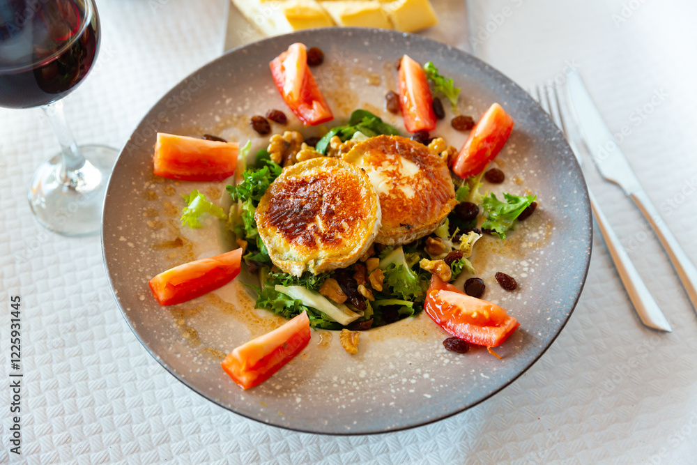 Appetizing salad with goat cheese, tomatoes and walnuts on a plate