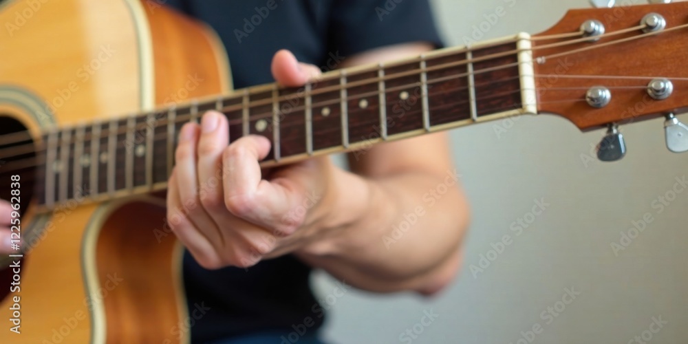 Fototapeta premium Close-up view of a person's hands delicately playing an acoustic guitar, fingers gently pressing the strings, showcasing the intricate details of the instrument and the musician's skill.