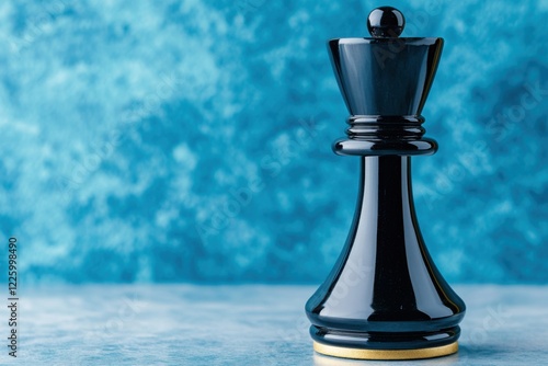 Black chess piece stands prominently against a textured blue background with dramatic lighting highlighting its elegant form and minimalist design photo