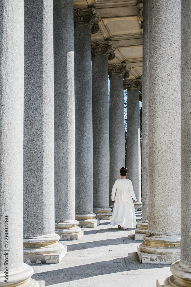 Young girl in First Communion dress among grand columns