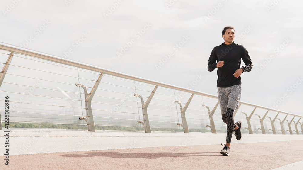 Young fit sporty sportsman athlete jogging running in fitness clothes trainers on city urban bridge in the morning doing warming-up exercises for slimming. Active lifestyle concept Young fit sporty sportsman athlete jogging running in fitness clothes trainers on city urban bridge in the morning doing warming-up exercises for slimming. Active lifestyle concept