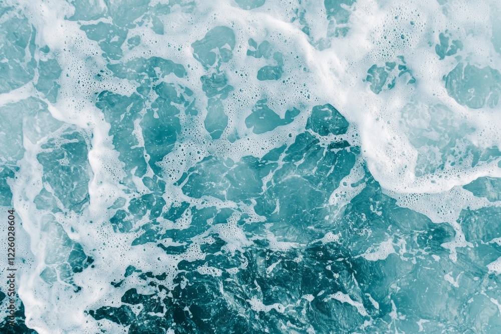 Obraz premium Gentle waves create white foam on the surface of turquoise ocean water, providing a serene and natural background perfect for various design projects