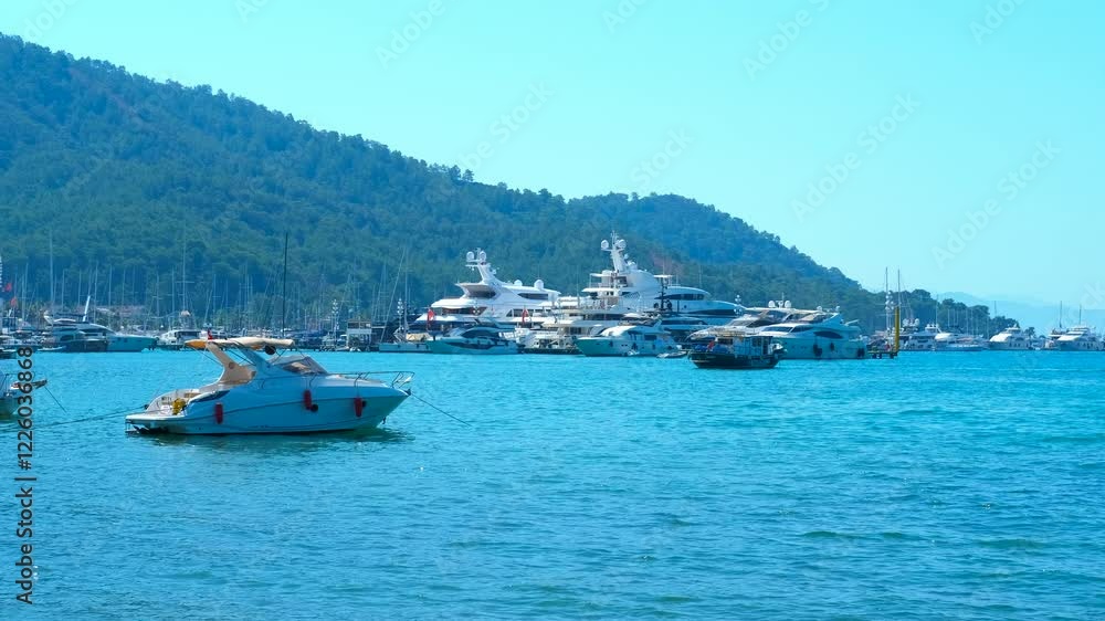 Turquoise sea water showcases luxury boats and yachts on a sunny summer day. Green mountain slopes create a stunning backdrop, enhancing the beauty of the coastal landscape Turquoise sea water showcases luxury boats and yachts on a sunny summer day. Green mountain slopes create a stunning backdrop, enhancing the beauty of the coastal landscape