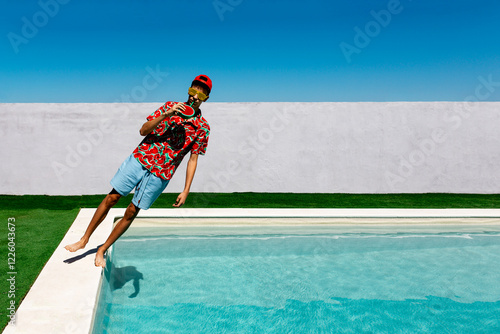 Teenager balancing on poolside with watermelon and sunglasses photo