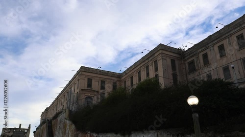 Exterior view of the historic Alcatraz building, standing strong against a clear blue sky. The iconic structure, with its weathered stone and distinctive architecture