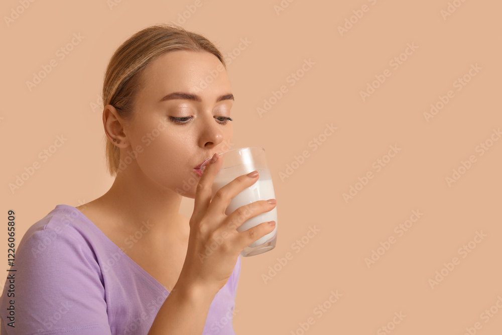 Pretty young woman drinking milk on beige background Pretty young woman drinking milk on beige background