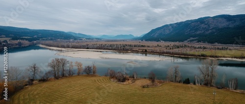 Aerial view of a river winding through a valley, showcasing a mix of grasslands and forests. Calm water reflects the overcast sky. , Chinook Cove, British Columbia, Canada photo