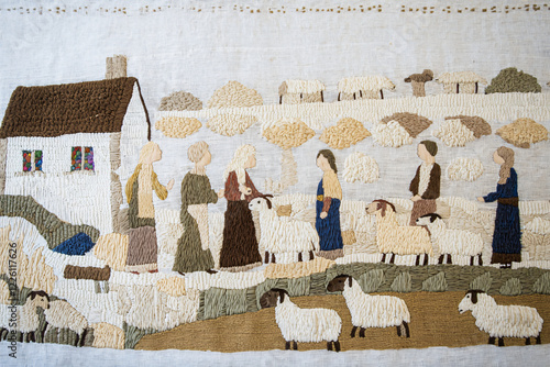 worn medieval tapestry illustrating villagers tending sheep, pastoral landscape, stone walls, authentic period details photo