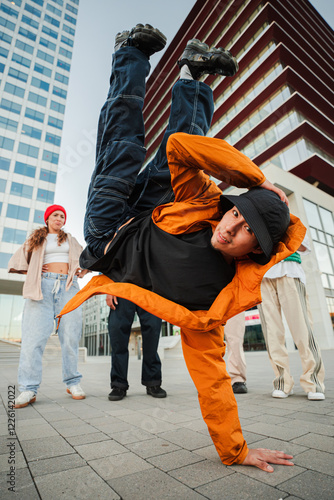 Obraz na plátne Energetic Breakdancer Showcasing a Skillful Freeze Move while Friends Support and Cheer him on during an Exciting Street Dance Performance with Enthusiasm and Passion for hip hop Culture