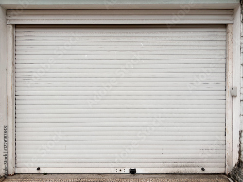 Closed white metal garage door with dirt stains
