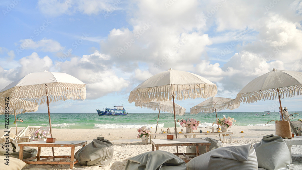 Fototapeta premium Beachside lounge featuring elegant bohemian-style umbrellas with fringe details, wooden tables and cozy bean bags.