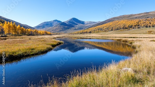 Winding river reflects distant mountains and golden autumn trees in a peaceful valley under a clear blue sky.