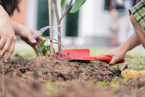 Kid's and mother's hands working together to plant a sapling in soil, promoting care, bonding, and sustainability in Thailand.