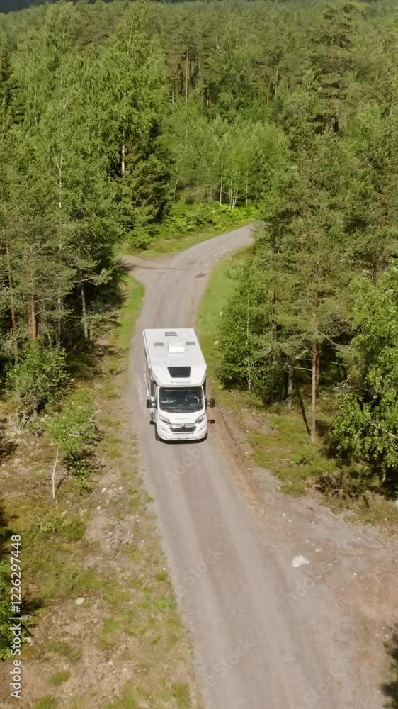 Vertical drone shot in front of a RV on a forest, dirt road in the Nordics Vertical drone shot in front of a RV on a forest, dirt road in the Nordics