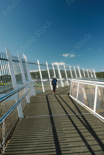 a woman with blonde hair, wearing a hat, was walking and enjoying the beauty around the Whangarei Town Basin