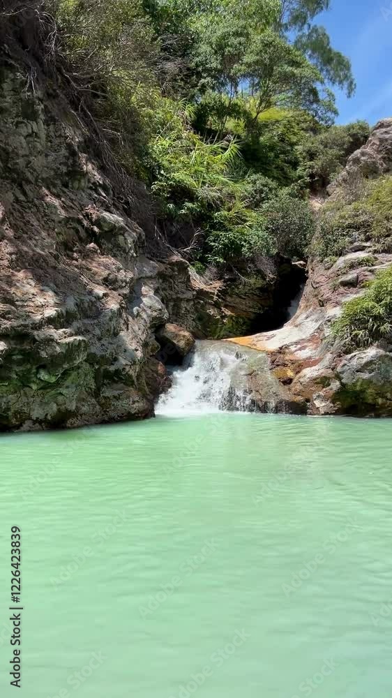 Fixed nature scene of water flowing into steaming natural hot springs surrounded by greenery in the mountains of Tomohon, South Sulawesi. Vertical View Fixed nature scene of water flowing into steaming natural hot springs surrounded by greenery in the mountains of Tomohon, South Sulawesi. Vertical View
