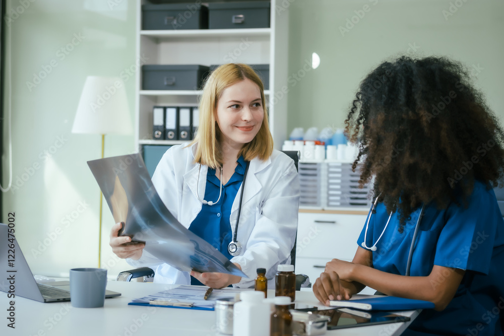 Fototapeta premium An African American female doctor and a white female doctor work at hospital desk, discussing patient treatment,medical analysis,healthcare strategies ensure quality medicine effective patient care