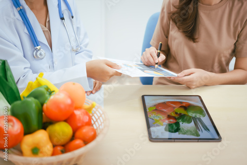 A young female nutritionist expert talks to a female patient at a table, recommending a healthy diet with vegetables and fruits to promote wellness, balanced nutrition, and effective weight loss photo