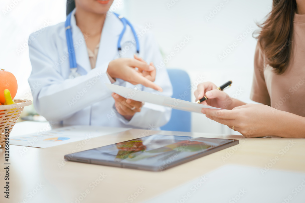 A young female nutritionist expert talks to a female patient at a table, recommending a healthy diet with vegetables and fruits to promote wellness, balanced nutrition, and effective weight loss