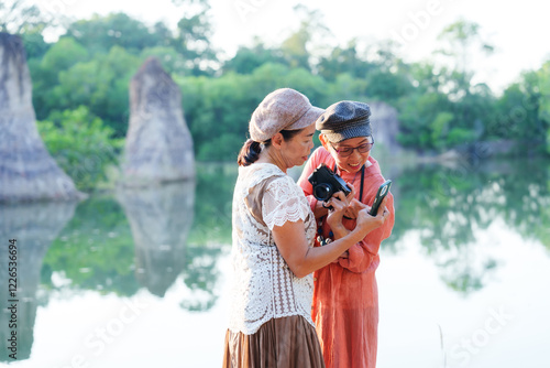 Senior Asian woman travels with close friend after retirement. Elderly Asian women laughing walking freely on nature trail expressing happiness enjoying fresh air feeling energetic during outdoor trip